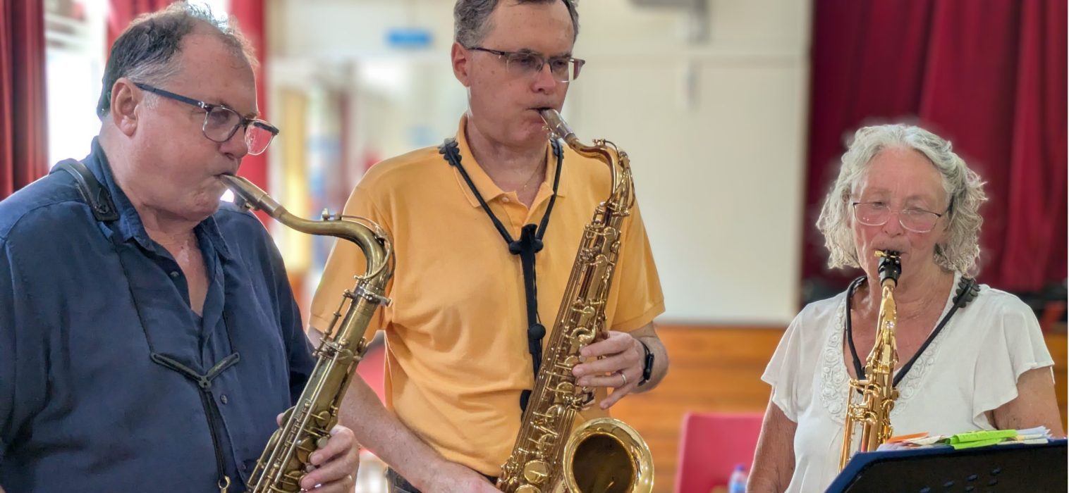 Three people playing tenor saxophones two men on left and one woman on right