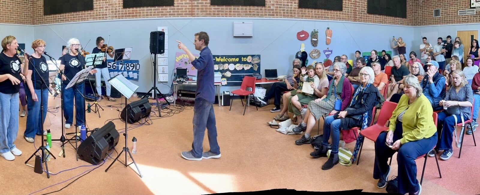 Richard Coffey Glover - centre, conducting the Lady Music Soul band on left, audience on right.